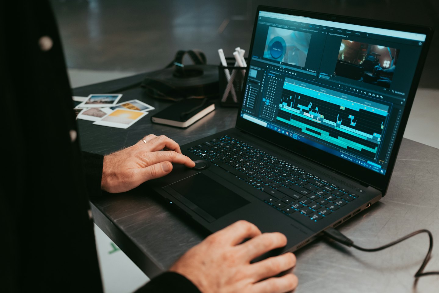 Kädet editoimassa videomateriaalia kannettavalla tietokoneella.