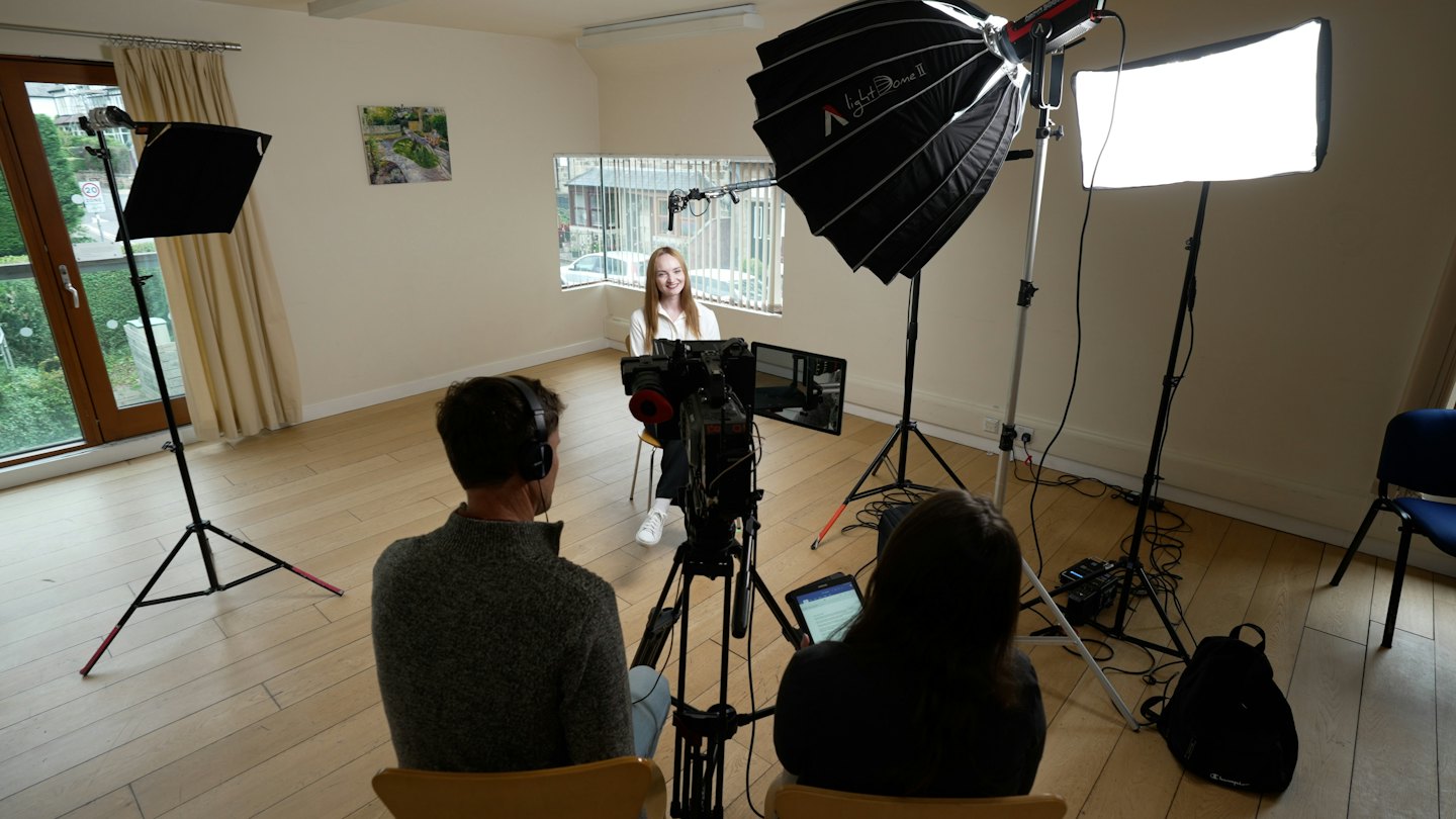 Nuori nainen hymyilee sisätiloissa videotuotantokuvauksissa.